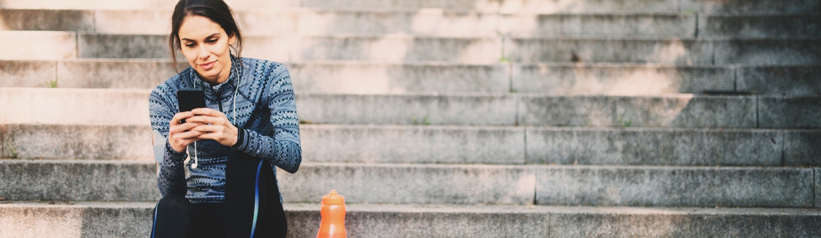 Woman sitting on outside steps viewing cell phone